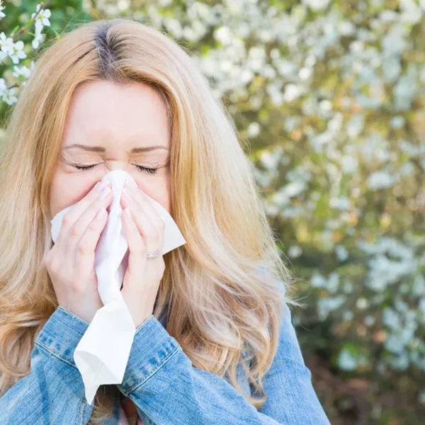 Seasonal allergies treatment — woman with allergy symptoms outdoors during pollen season